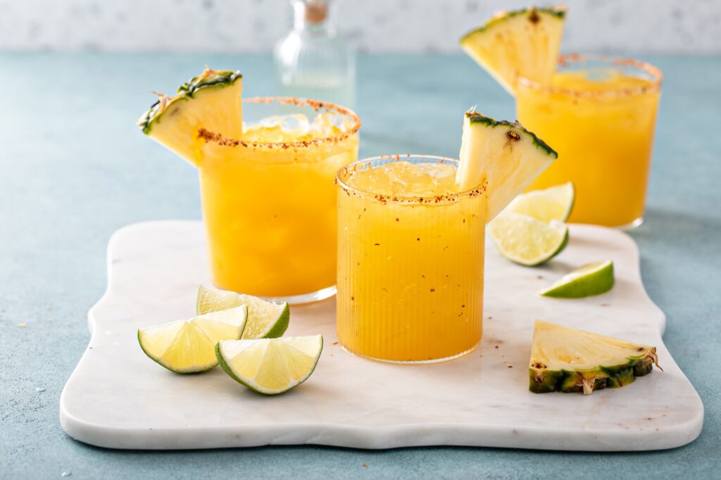 Pineapple margarita cocktail in glasses with tajin rim